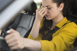 mujer conduciendo teniendo dolor cabeza