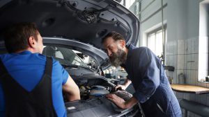Mecánicos hablando en taller sobre el mantenimiento preventivo del coche